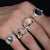 Close up on a hand of four handmade silver rings with opal and labradorite set stones.