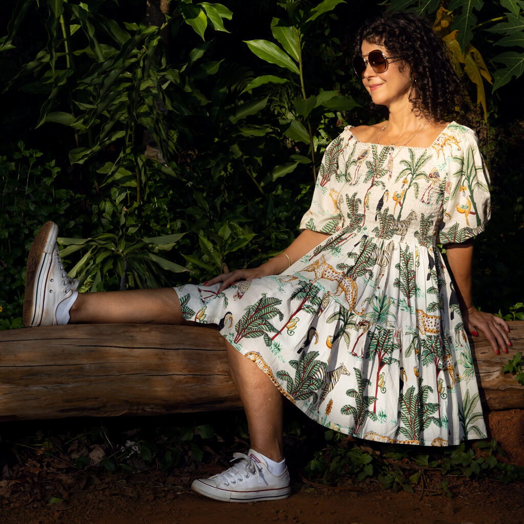 Lady seated in the jungle wearing a tropical print cotton dress.