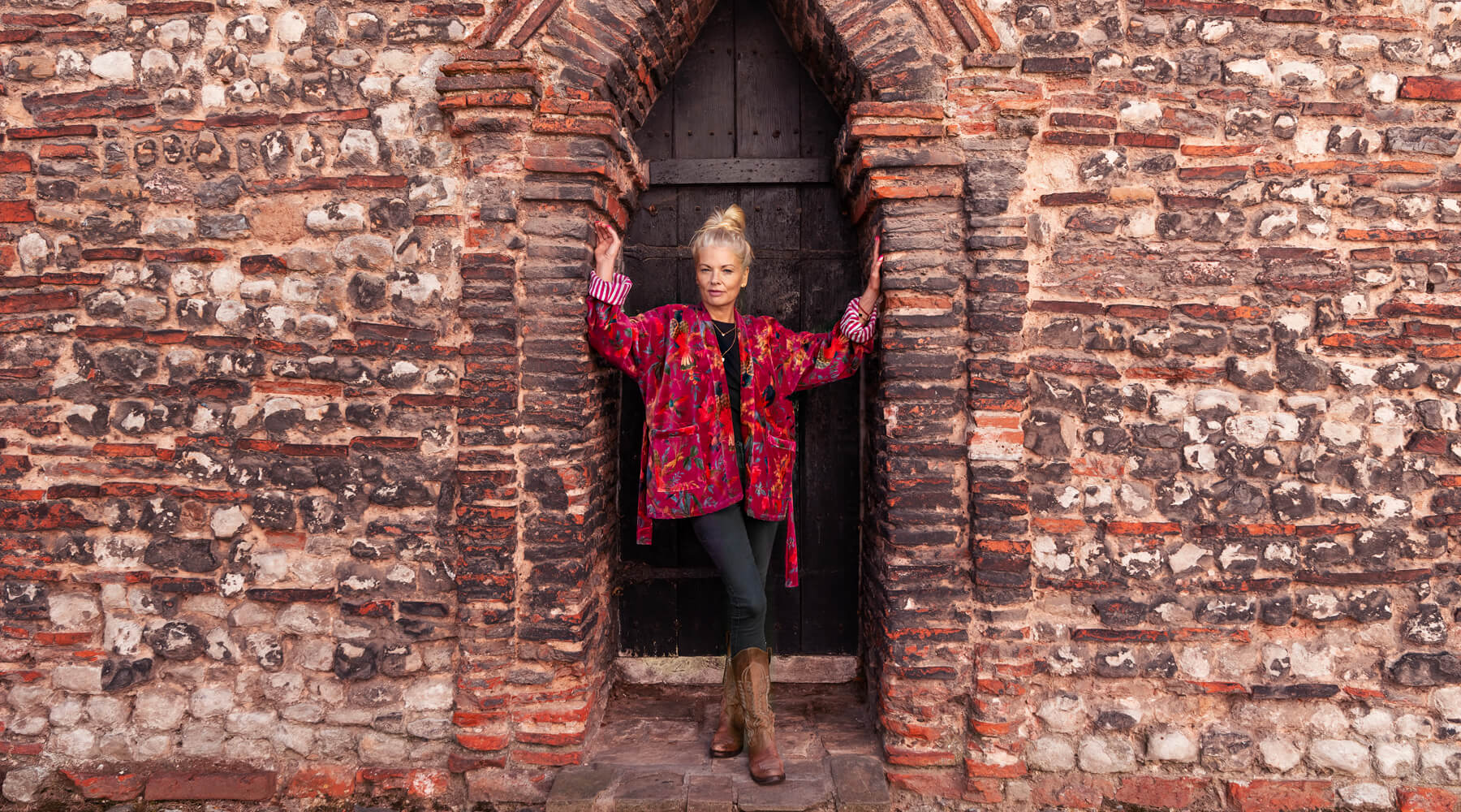 Woman in velvet jacket standing in old saxon doorway.