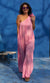 Lady walking in a pink one strap jumpsuit against a blue wall.
