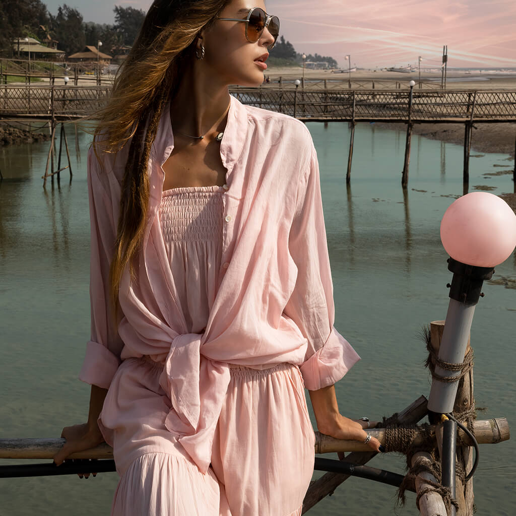Beautiful girl on bridge wearing a pink shirt and jumpsuit at sunset.