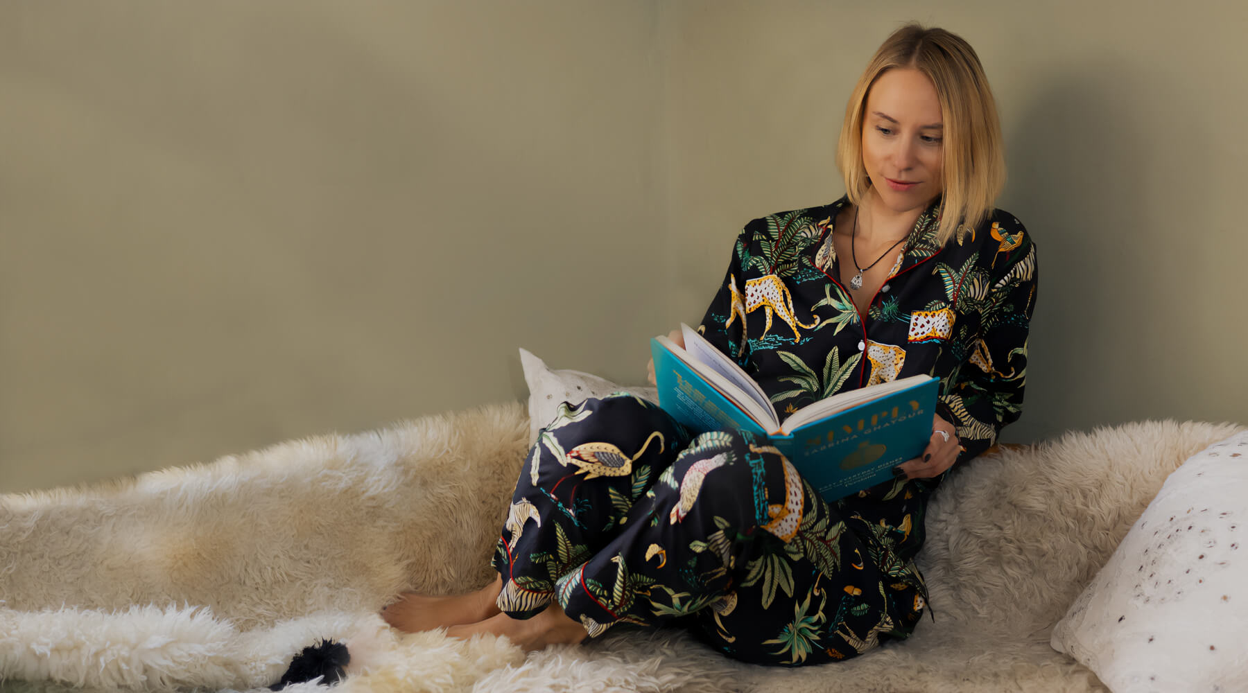 Girl relaxing in jungle print pyjamas while reading a book